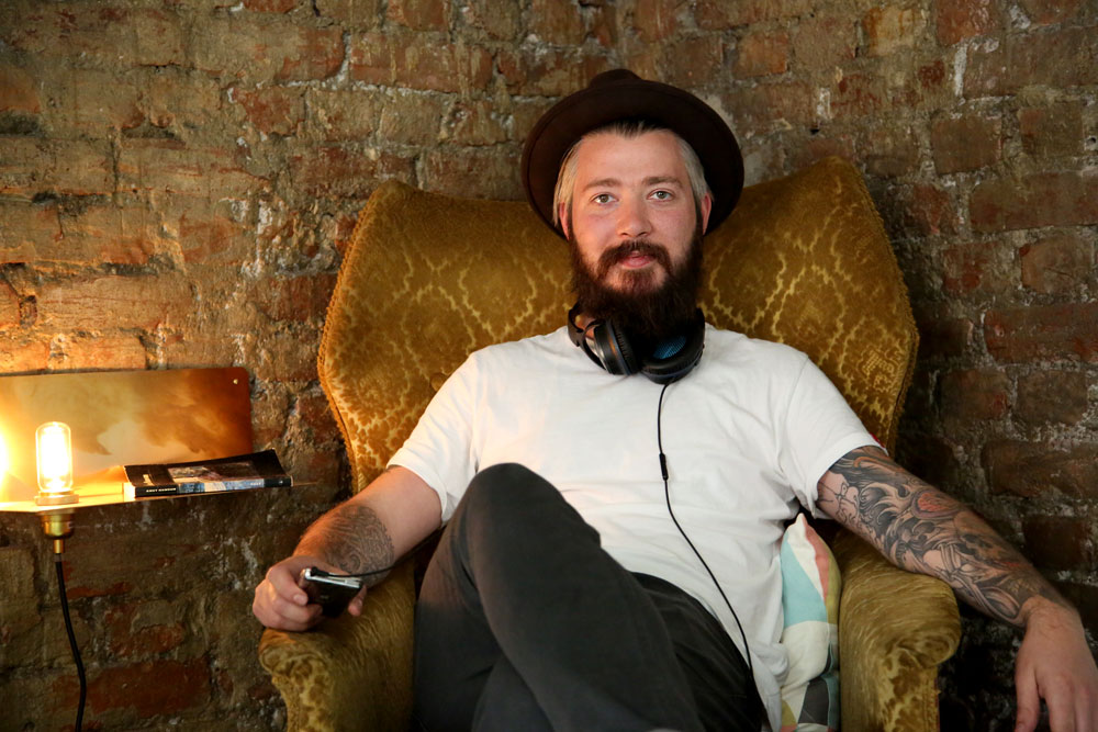 Even Ramsvik i godstolen hjemme på Tøyen i Oslo. Han er veldig glad i musikk, men har hverken CD-spiller eller platespiller. Hjemme bruker han en skramlete gammel mobiltelefon med sprukket glass gjennom Apple TV når han hører musikk. Foto: Erik Valebrokk