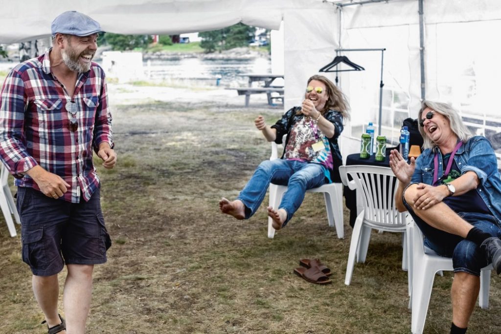 Backstage under Treungenfestivalen i august i fjor, der Lars Christian Narum forteller en historie som er så god at Lars Håvard og Aslag praktisk talt letter fra stolen. Foto: Trygve Indrelid